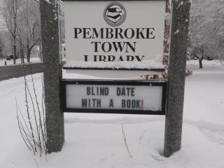 White "Pembroke Town Library" sign with snow on ground