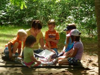 Image of children gathered around an adult reading a book