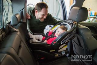 Adult putting child in a car seat